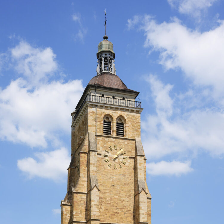 Historic stone clock tower against a blue sky with clouds.